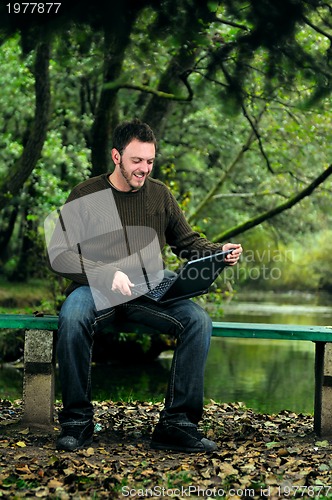 Image of young businessman working on laptop outdoor