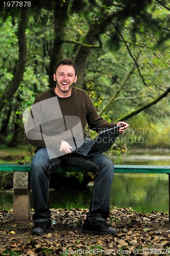 Image of young businessman working on laptop outdoor