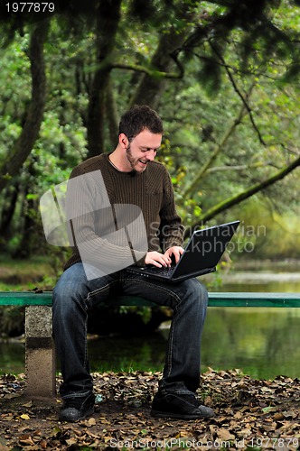 Image of young businessman working on laptop outdoor