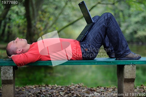 Image of young businessman outdoor working on laptop