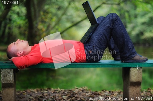 Image of young businessman outdoor working on laptop