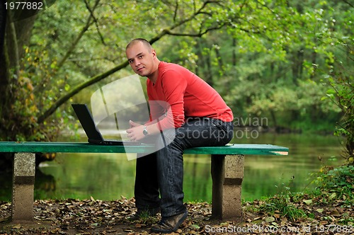 Image of young businessman in red shirt working on laptop 