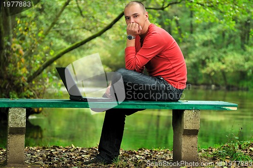 Image of young businessman in red shirt working on laptop 