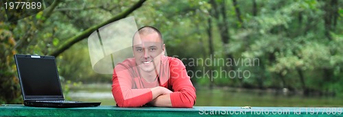 Image of young businessman working on laptop outdoor