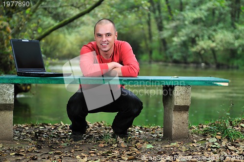 Image of young businessman working on laptop outdoor