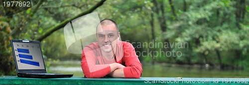 Image of young businessman in red shirt working on laptop 