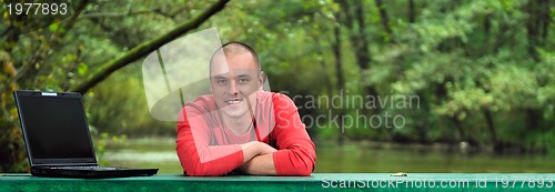 Image of young businessman outdoor working on laptop