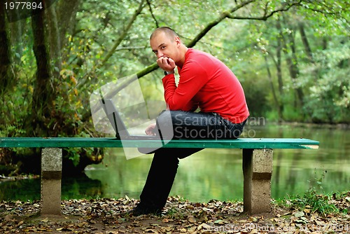 Image of young businessman working on laptop outdoor