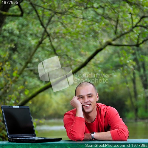 Image of young businessman working on laptop outdoor
