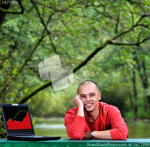 Image of young businessman outdoor working on laptop