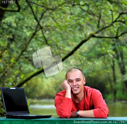 Image of young businessman outdoor working on laptop