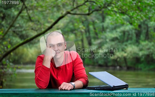 Image of young businessman outdoor working on laptop