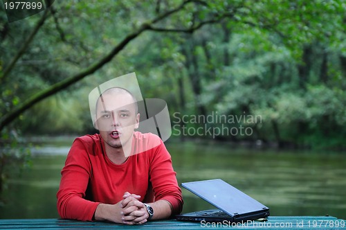 Image of young businessman outdoor working on laptop