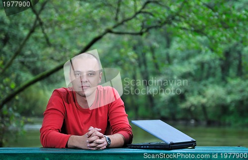 Image of young businessman outdoor working on laptop