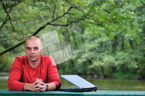 Image of young businessman working on laptop outdoor
