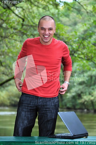 Image of young businessman working on laptop outdoor