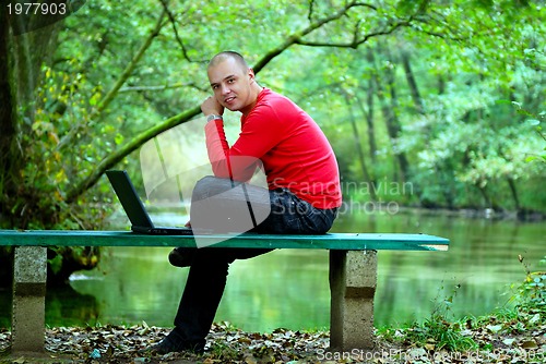 Image of young businessman outdoor working on laptop