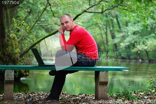 Image of young businessman working on laptop outdoor