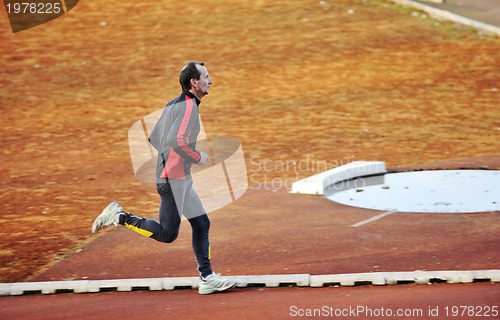 Image of adult man running on athletics track