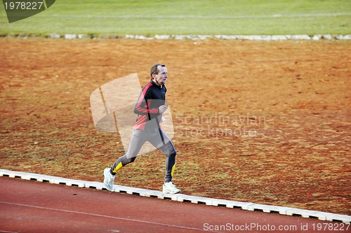 Image of adult man running on athletics track