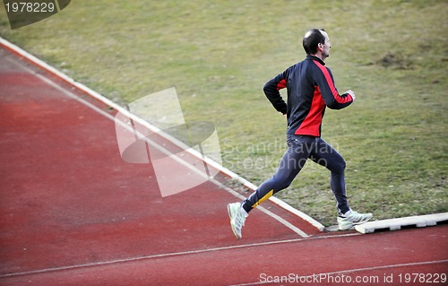 Image of adult man running on athletics track