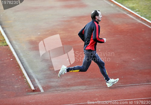 Image of adult man running on athletics track