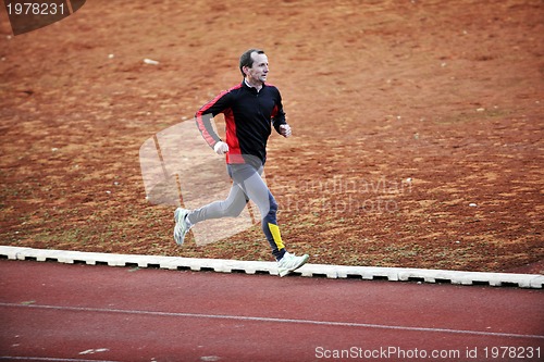 Image of adult man running on athletics track