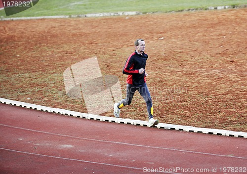 Image of adult man running on athletics track