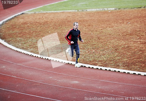 Image of adult man running on athletics track