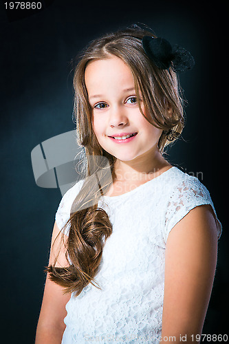 Image of cute girl in white lacy dress and black hat on dark background