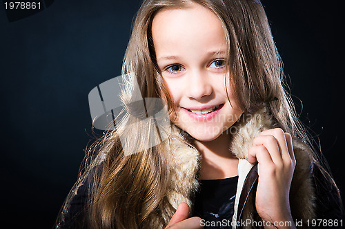 Image of  girl with fair long hair in fur vest on dark background