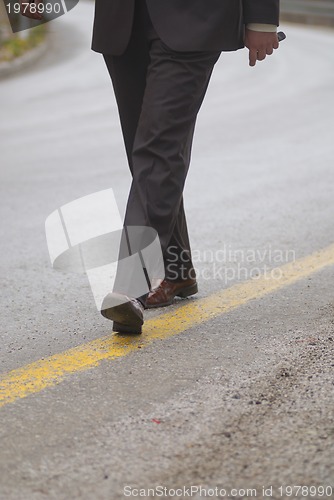 Image of .businessman walking on yellow line