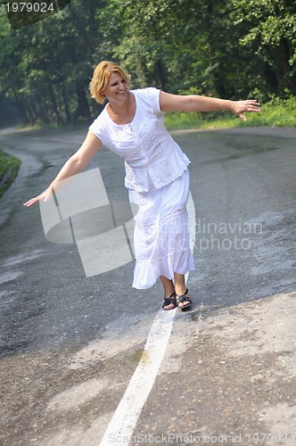 Image of middle age woman walk on white line on road outdoor