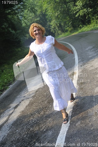 Image of middle age woman walk on white line on road outdoor