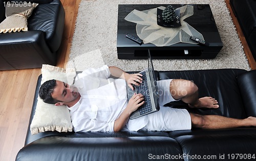 Image of Portrait of a relaxed young guy using laptop at home