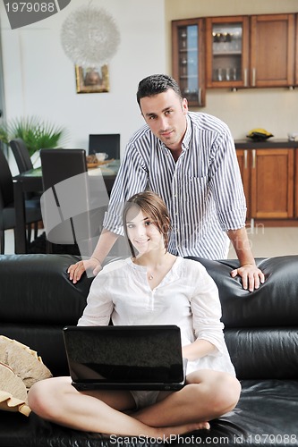 Image of joyful couple relax and work on laptop computer at modern home