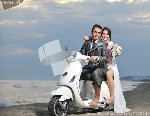 Image of just married couple on the beach ride white scooter