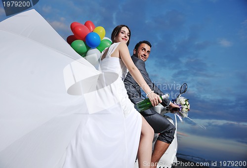 Image of just married couple on the beach ride white scooter