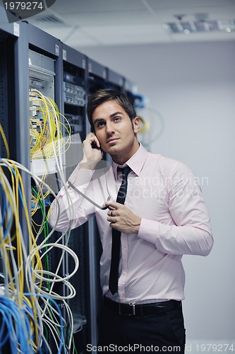 Image of it engeneer talking by phone at network room