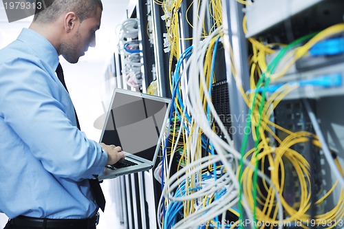 Image of businessman with laptop in network server room