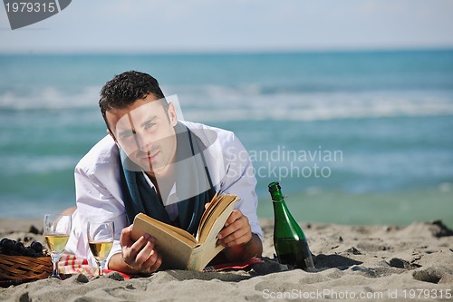 Image of man reading book at beach