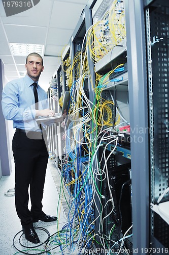 Image of businessman with laptop in network server room