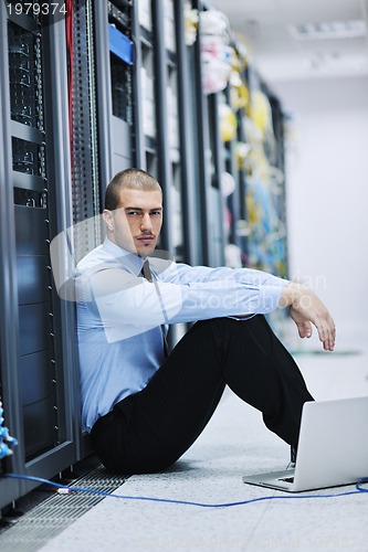 Image of businessman with laptop in network server room