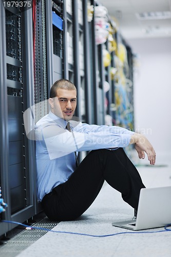 Image of businessman with laptop in network server room