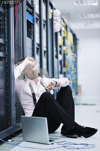 Image of businessman with laptop in network server room