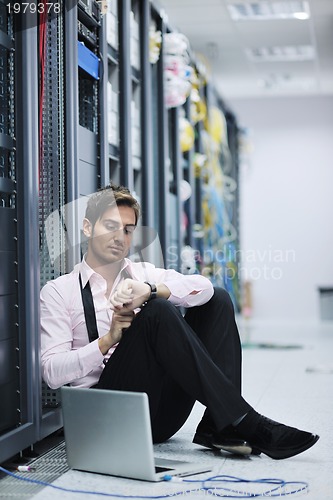 Image of businessman with laptop in network server room