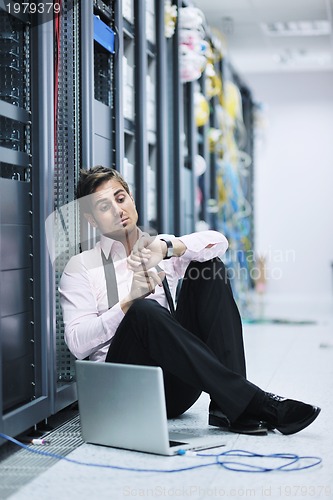 Image of businessman with laptop in network server room