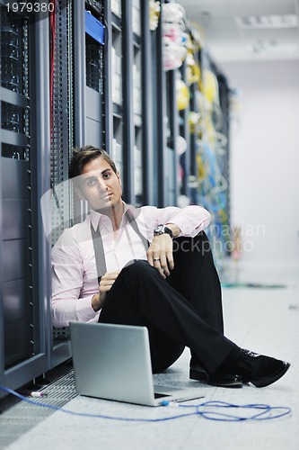 Image of businessman with laptop in network server room