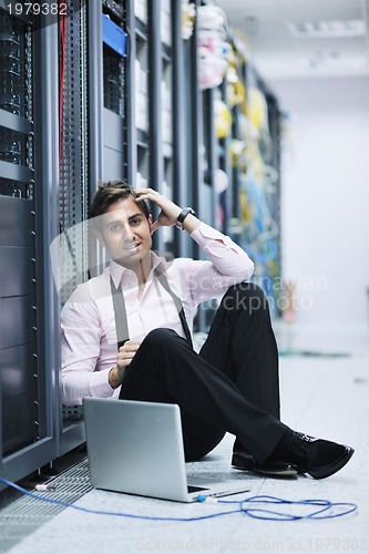 Image of businessman with laptop in network server room