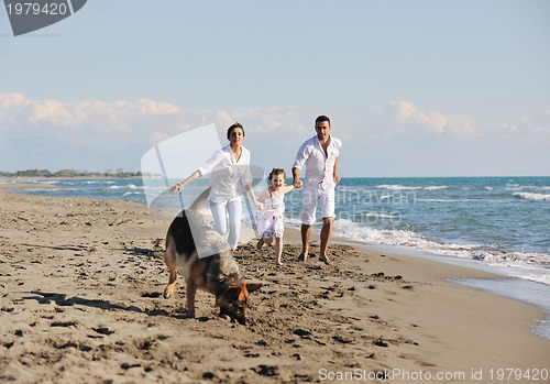 Image of happy family playing with dog on beach